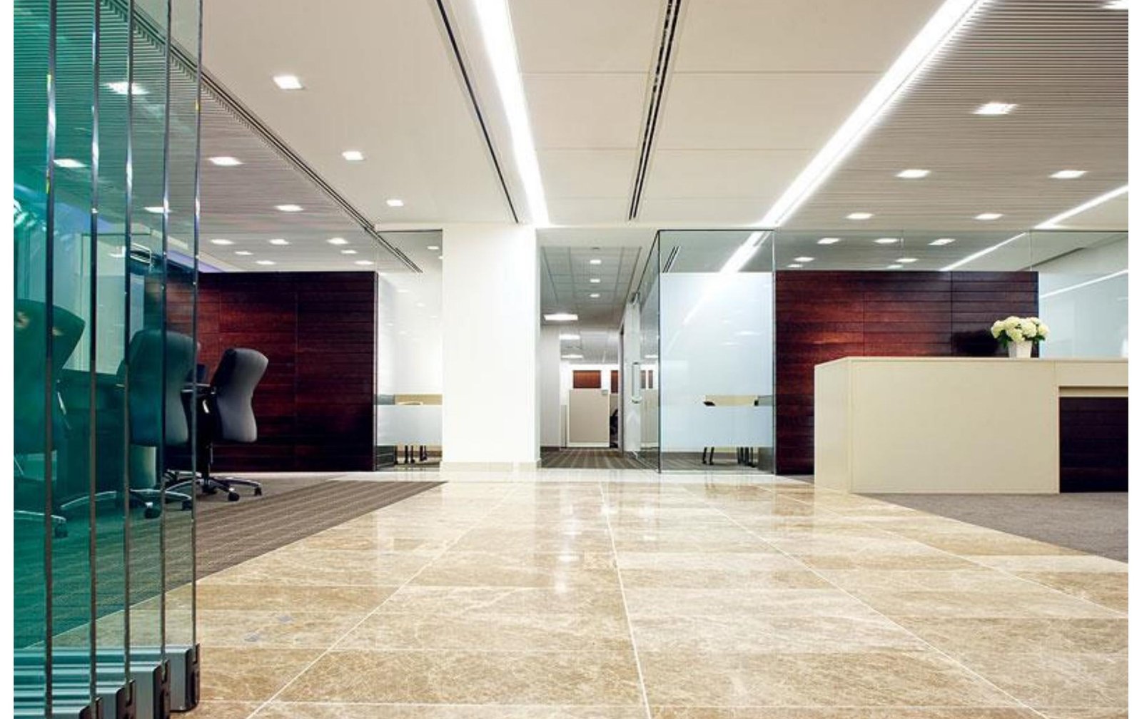 Widmeyer Communications office reception lobby in Washington DC featuring polished travertine flooring, wood paneling, and glass partitions &mdash; 16,000 square foot Class-A office fit-out by Barbara D. Currie.